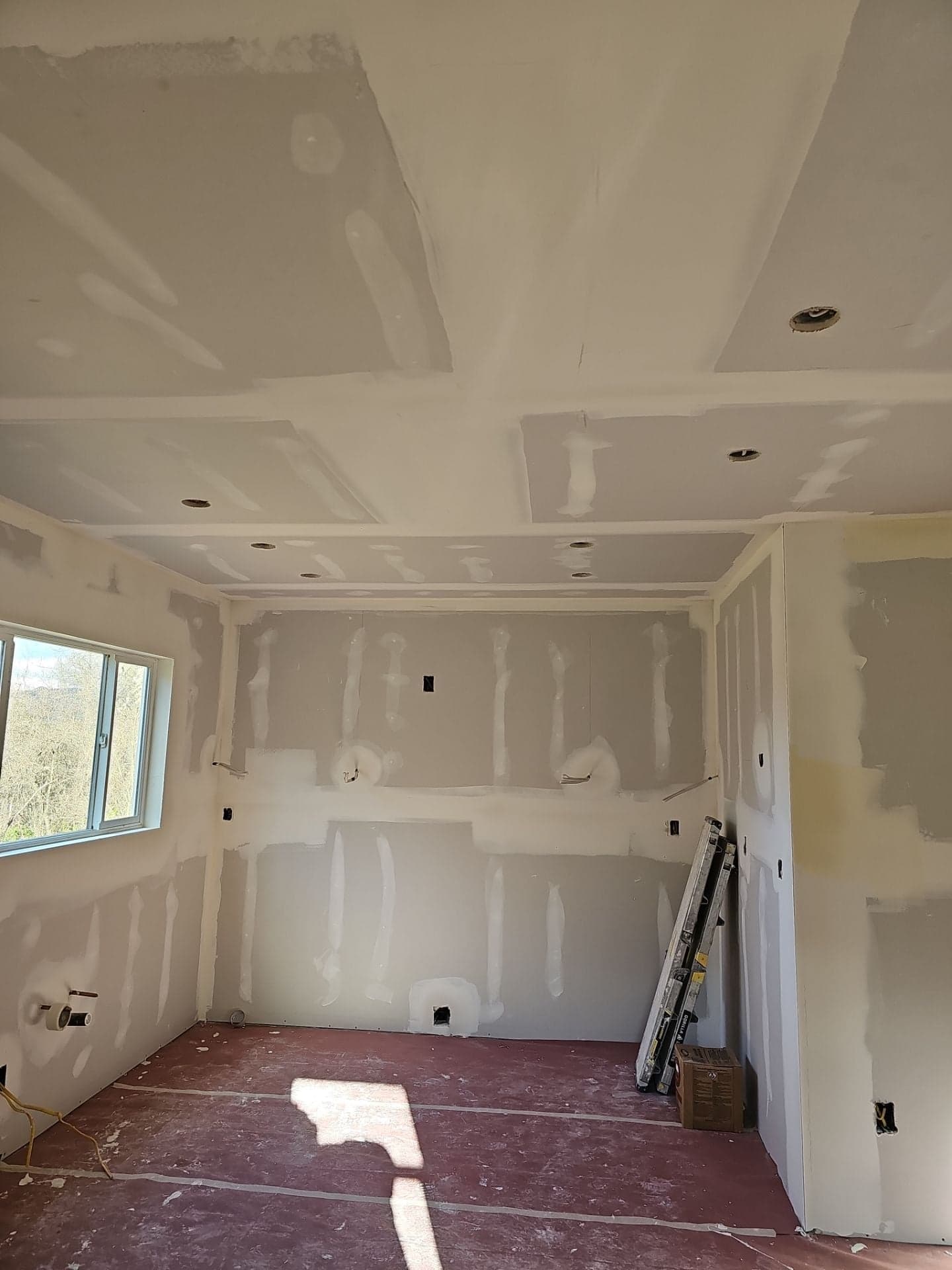 Newly drywalled room with taped seams, recessed can lights, and a new window during an RLS Custom Carpentry remodel in Mendocino County, CA