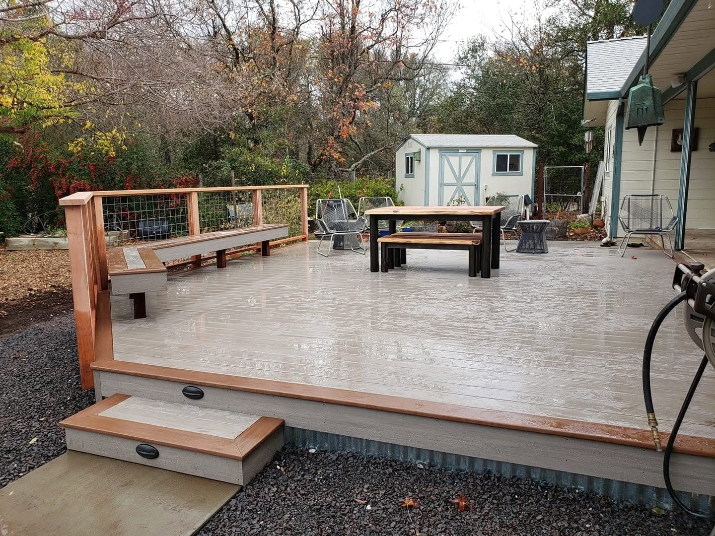 Finished composite deck with redwood railing, built-in bench seating and recessed step lights in a backyard, built by RLS Custom Carpentry, Mendocino County CA