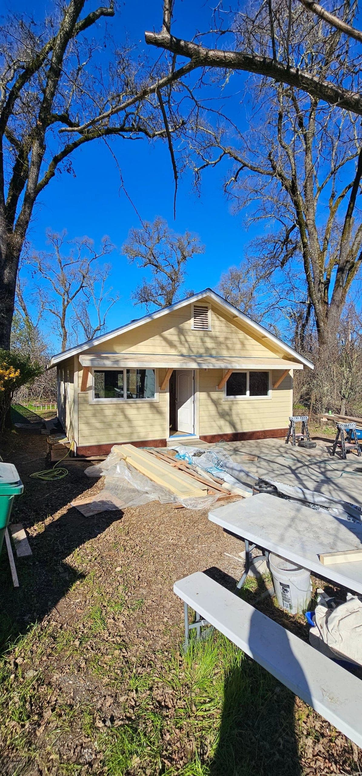Yellow bungalow exterior with fresh lap siding and new windows during a full home remodel at 5160 Burke Hill Rd in Mendocino County by RLS Custom Carpentry