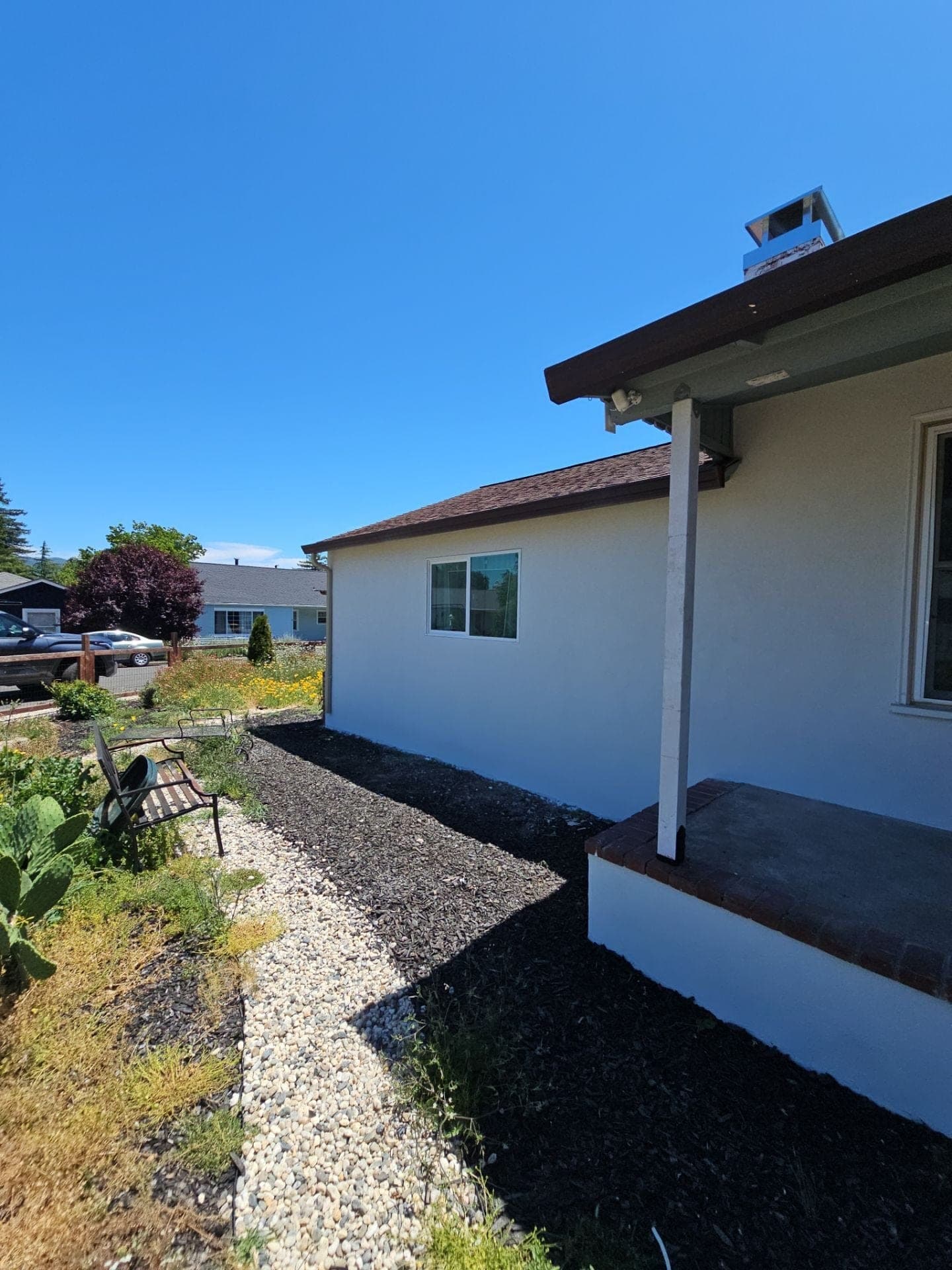 Remodeled white stucco home with covered porch, brick-capped step, and tidy landscaping by RLS Custom Carpentry in Mendocino County, CA