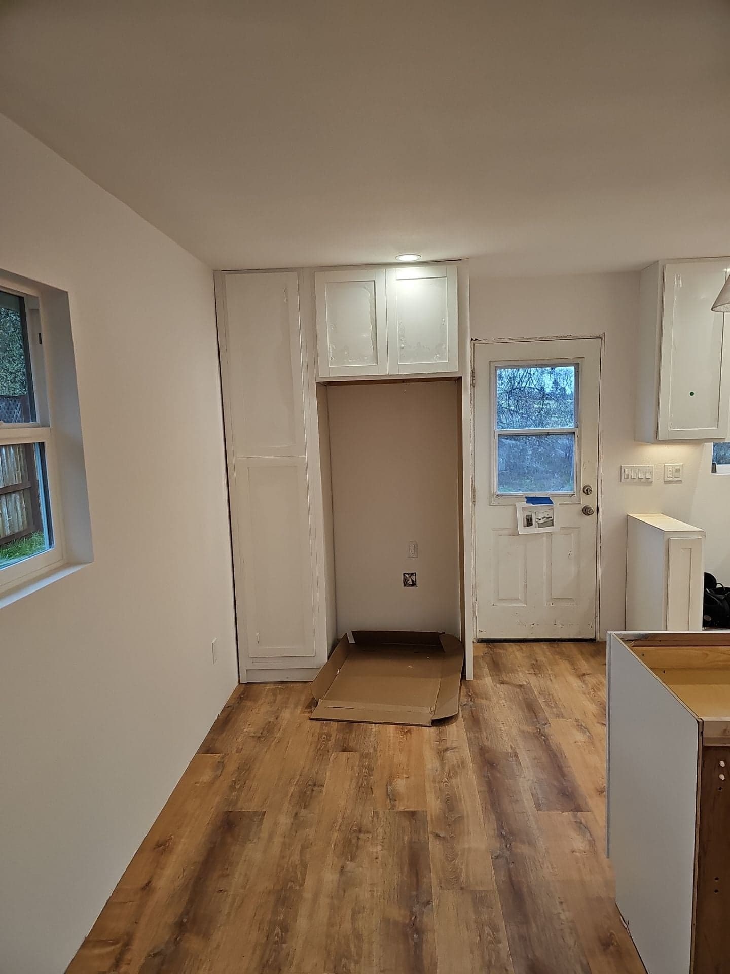 Completed kitchen remodel at 5160 Burke Hill Rd in Mendocino County featuring new luxury vinyl plank flooring, white pantry cabinetry and a fresh exterior door by RLS Custom Carpentry