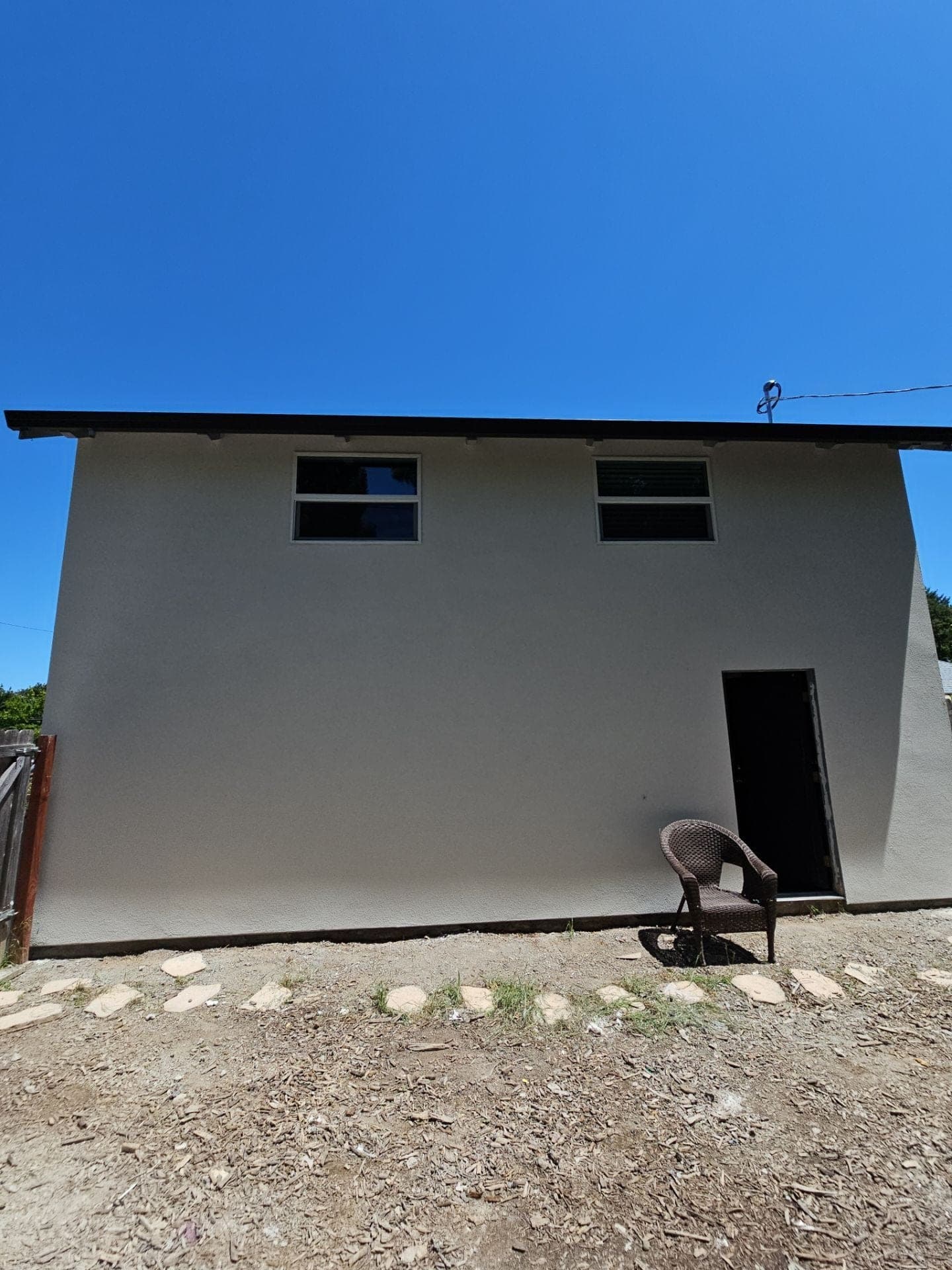 Finished rear elevation of a two-story addition with tan stucco, new windows and exterior door completed by RLS Custom Carpentry in Mendocino County, CA