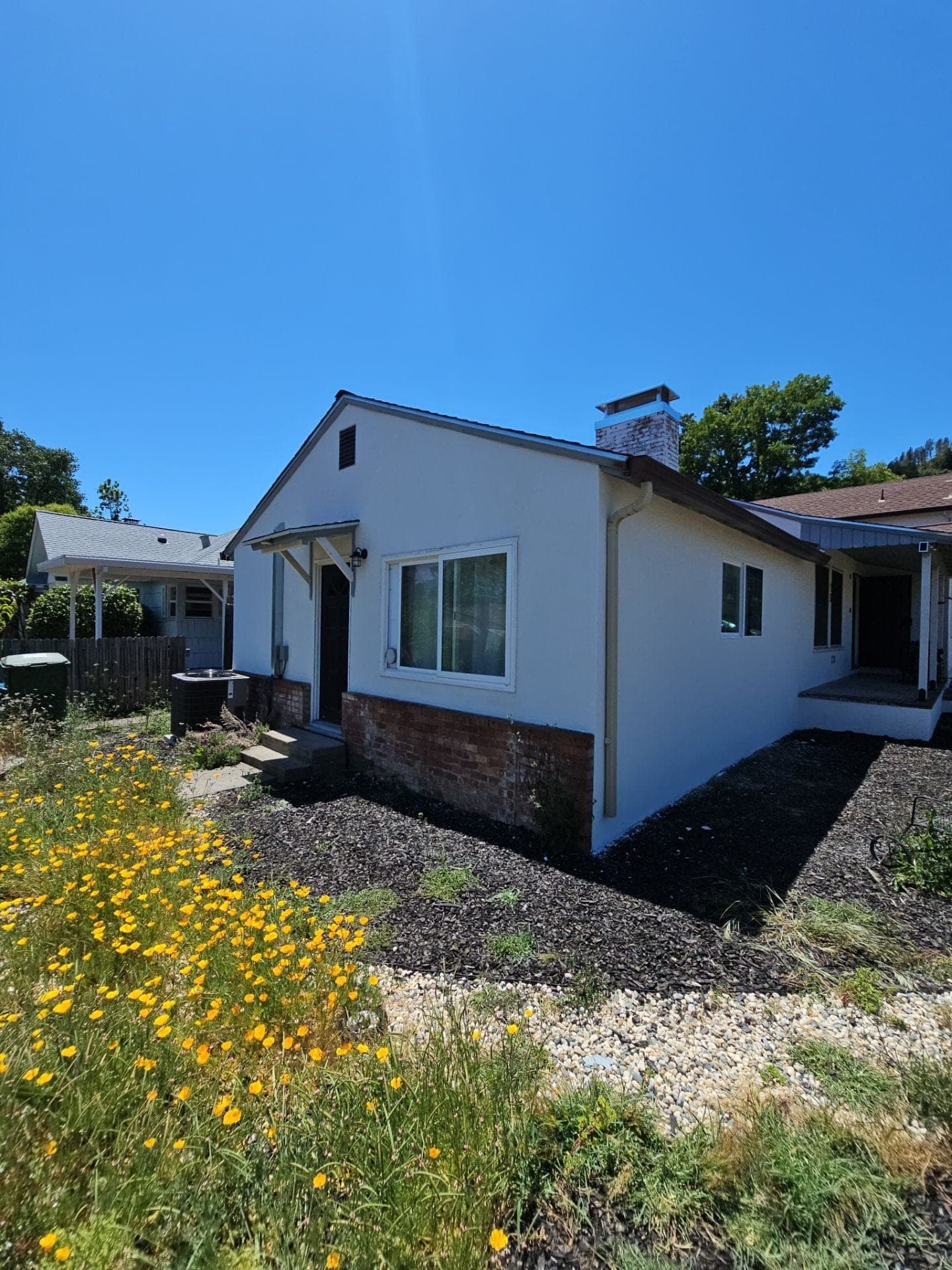 Completed single-story home remodel with fresh white stucco, brick wainscot accent, and new windows by RLS Custom Carpentry in Mendocino County, CA