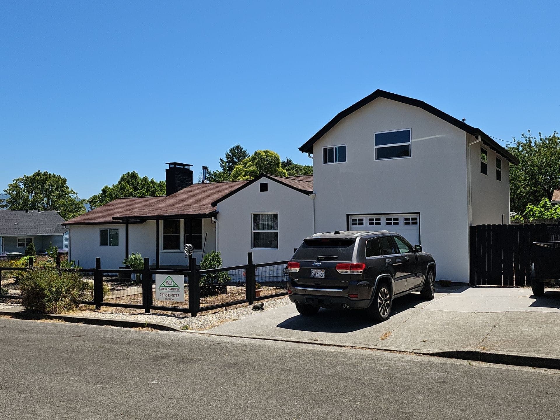 Completed home addition and remodel by RLS Custom Carpentry at 15 Mill Ct in Mendocino County CA, showing a new two-story wing with attached garage joined to the original single-story house with fresh white stucco and a dark composition roof