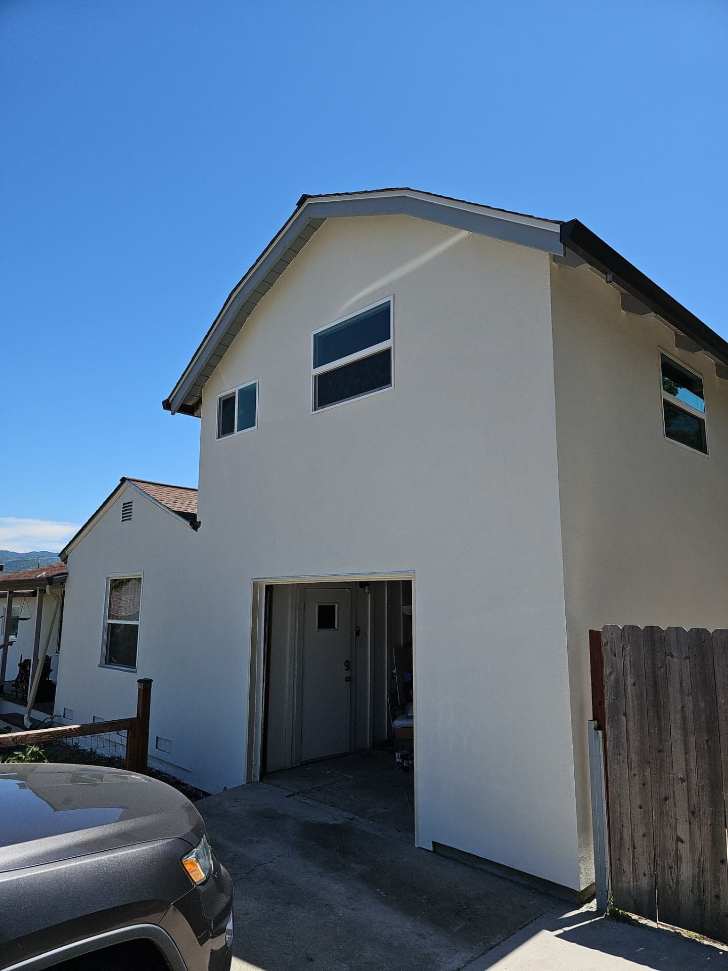 Completed two-story home addition with smooth white stucco finish and new windows, tied into the original house, built by RLS Custom Carpentry in Mendocino County, CA