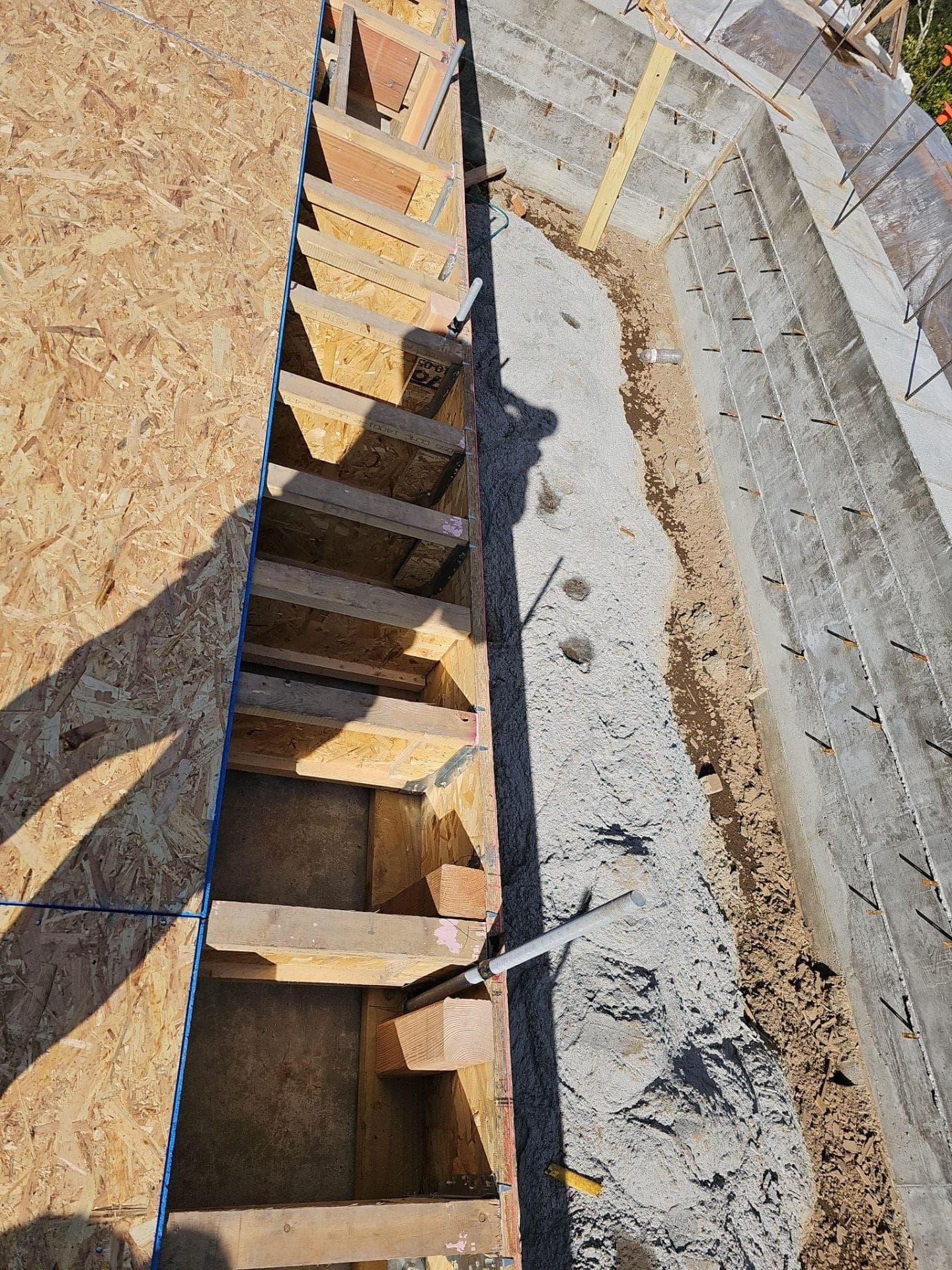 Floor joist framing set against a new poured concrete foundation wall at 3600 White Sulphur Spring Rd, built by RLS Custom Carpentry in Mendocino County, CA