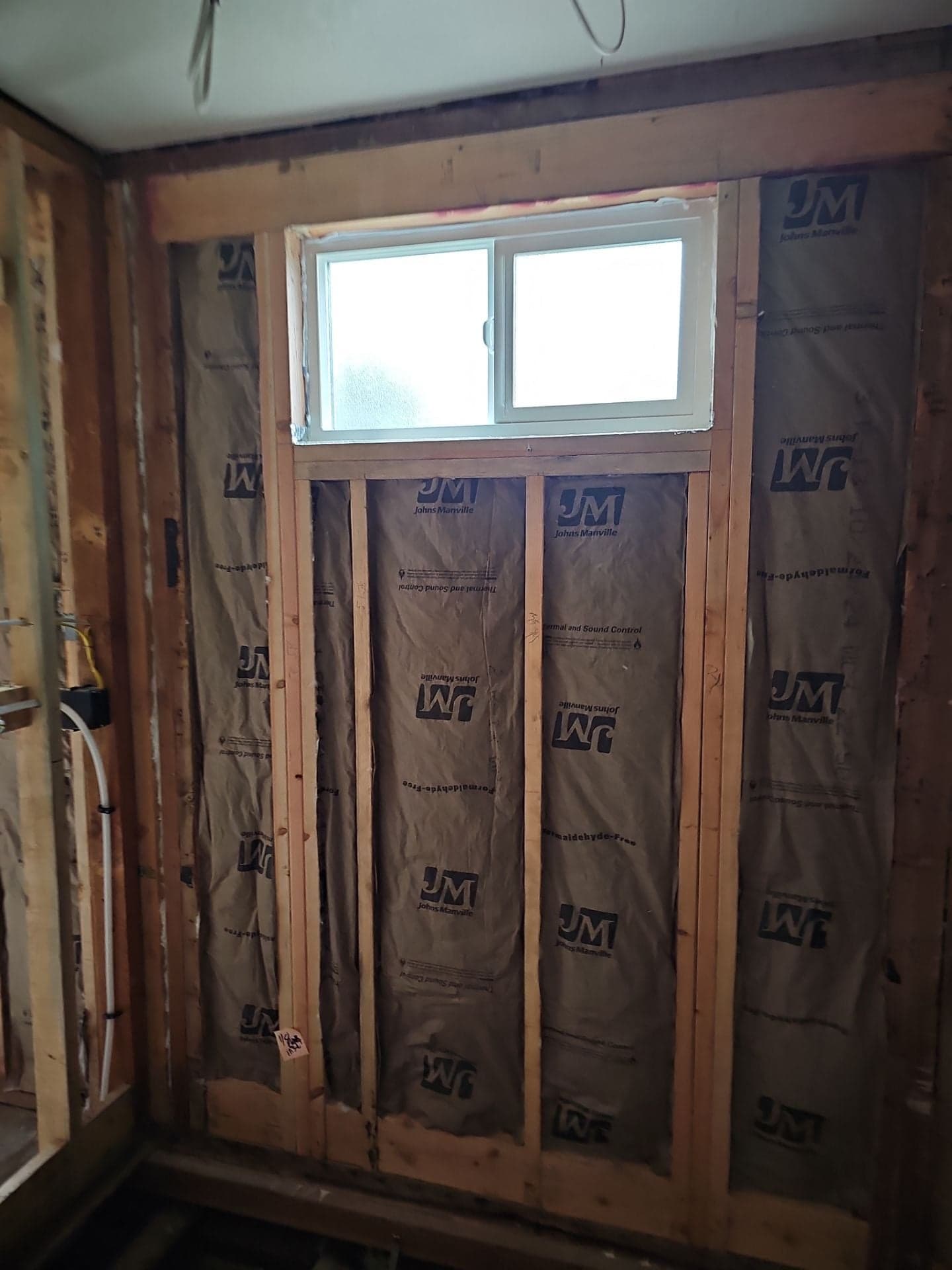 New framing, insulation, and a freshly installed slider window during a Mendocino County home remodel by RLS Custom Carpentry