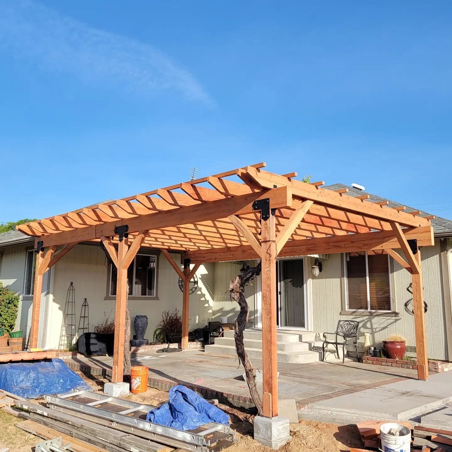 Custom redwood backyard pergola with lattice roof and black steel brackets built over a patio in Mendocino County, California