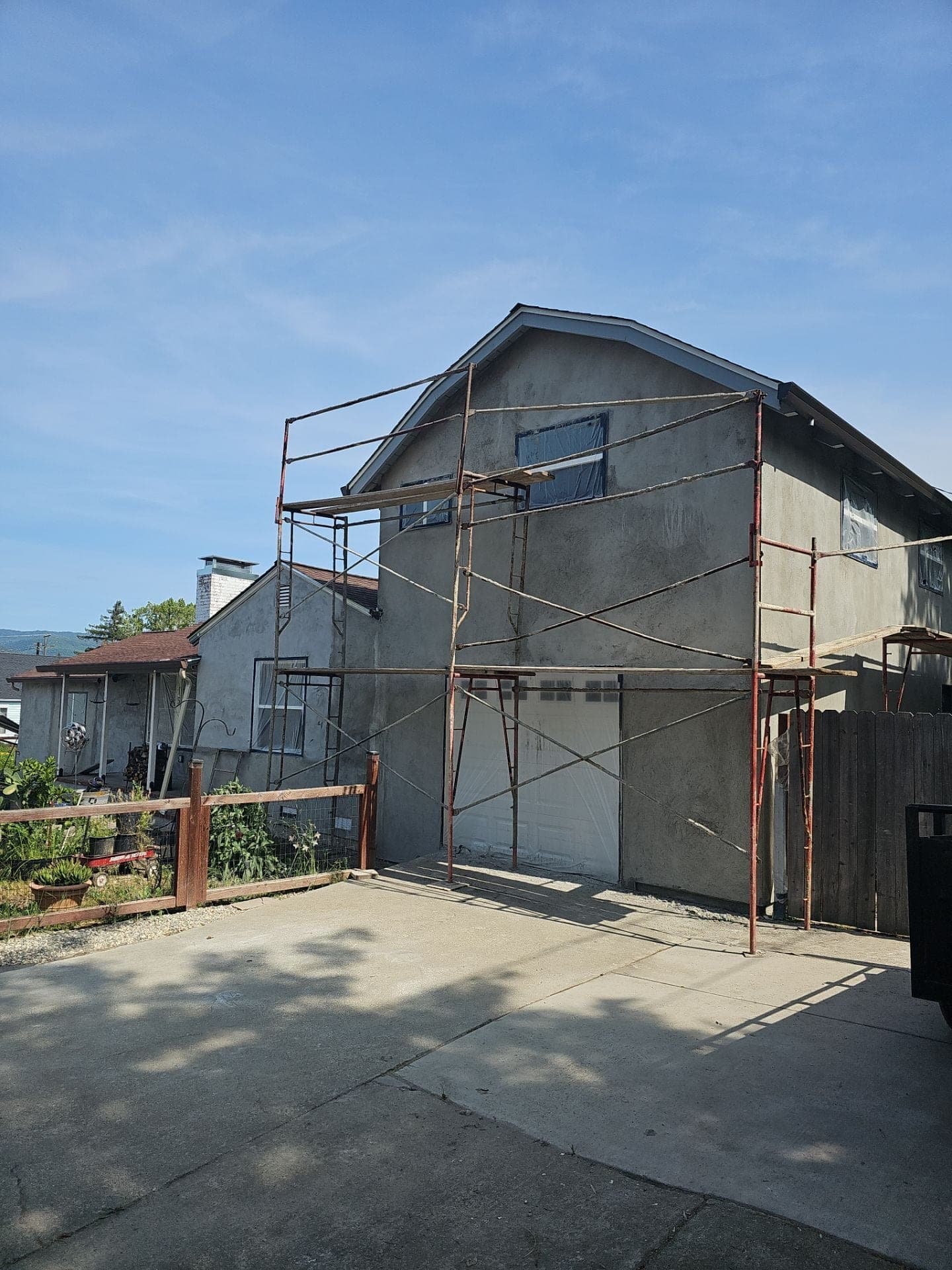 Two-story home addition with fresh gray stucco scratch coat and scaffolding still in place during an addition project by RLS Custom Carpentry in Mendocino County, CA