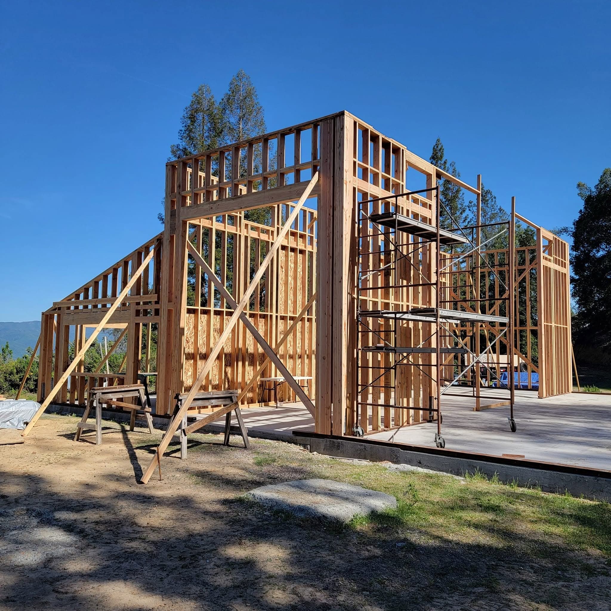 New construction wood stud-wall framing with scaffolding and braced walls on a slab foundation in rural Mendocino County, CA, built by RLS Custom Carpentry
